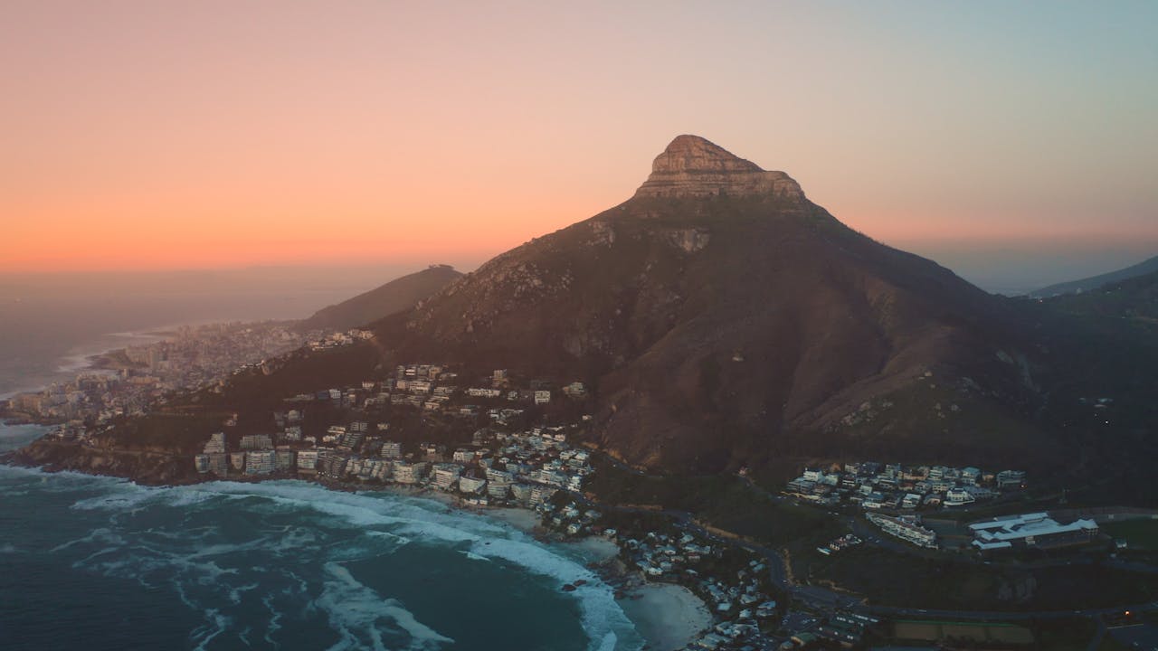 A breathtaking aerial view of Cape Town with Lion's Head mountain at sunset, showcasing the coastal landscape.